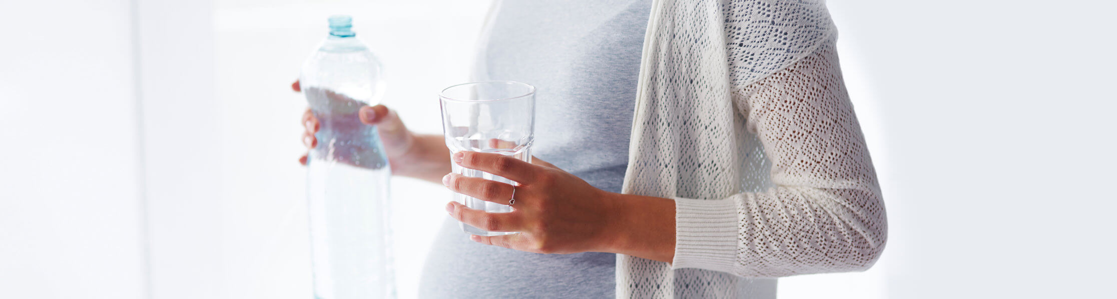 pregnant woman holding a water bottle and water glass