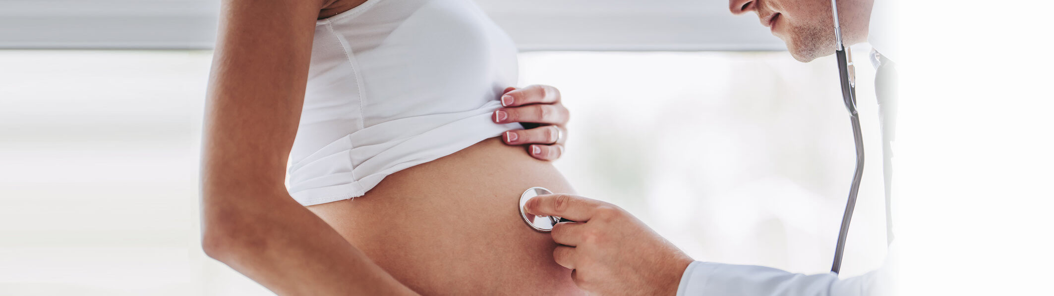 a pregnant belly with a physician holding a stethoscope up to it