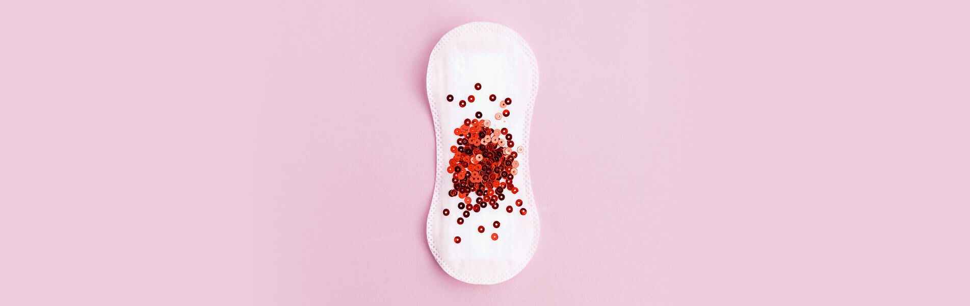 feminine hygiene pad with red sequins scattered over it in representative pattern of a period