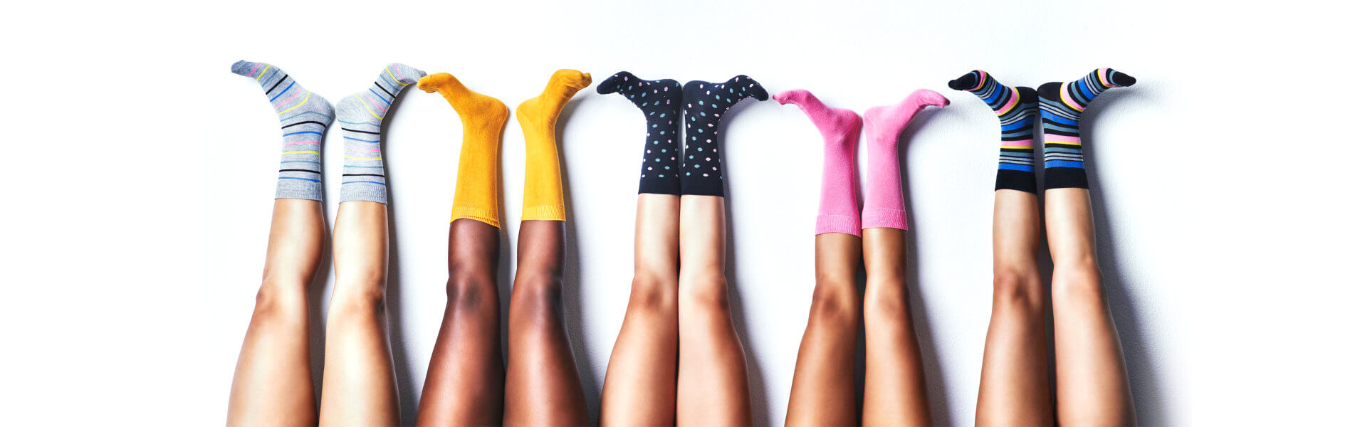 a series of 4 sets of legs sticking up with various coloured socks on each