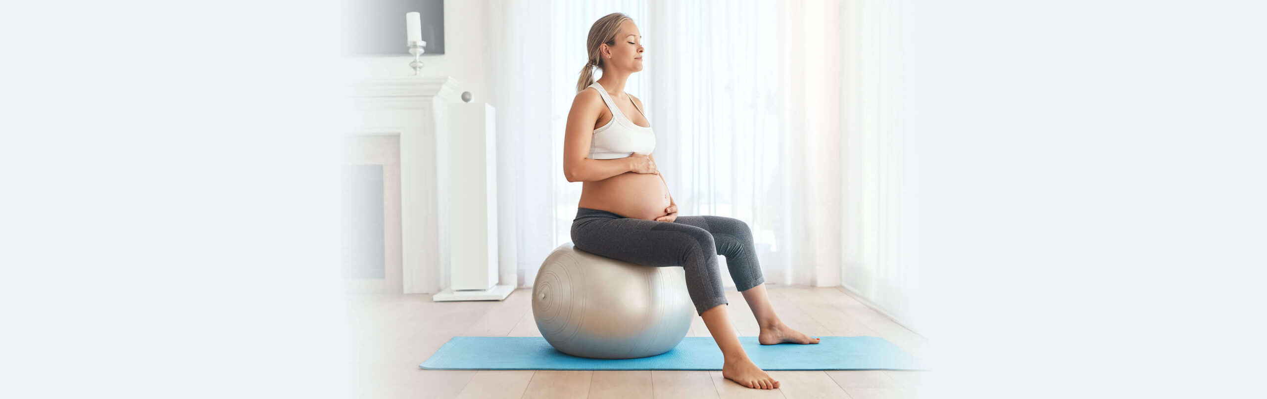 pregnant woman managing labour pain by sitting on an exercise ball holding her belly with eyes closed